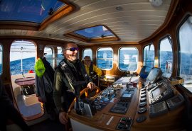 Crew member at helm in wheelhouse of Valiente