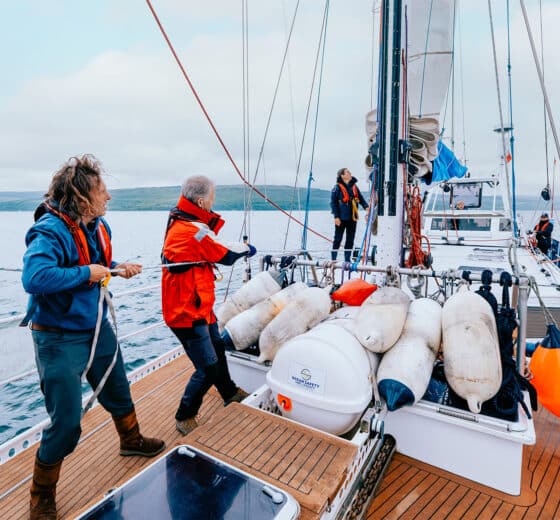 Zuza expedition yacht guests onboard sailing pulling ropes raising sail
